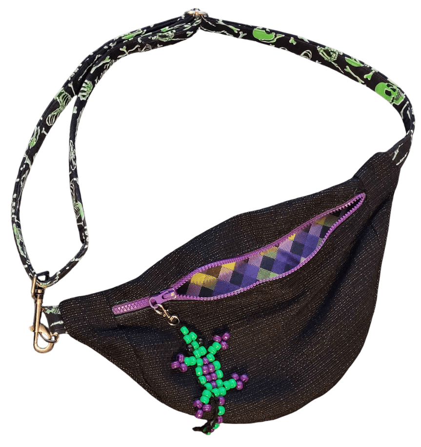 A black belt back with a purple zipper, green skull covered strap, and a green and purple bead lizard hanging from the zipper pull.